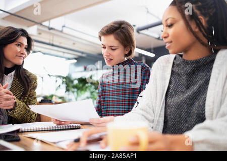 Businesswomen discussing paperwork in meeting Stock Photo