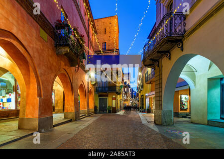 Narrow cobblestone street with Christmas illumination in old town of Alba in Piedmont, Northern Italy. Stock Photo