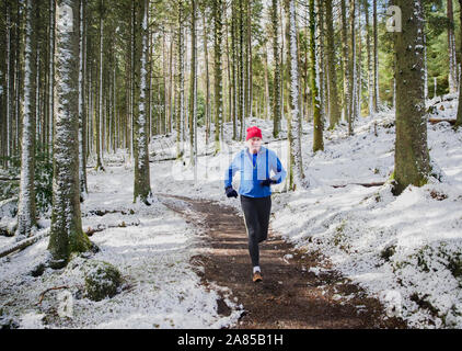 Active senior man jogging on trail in snowy woods Stock Photo