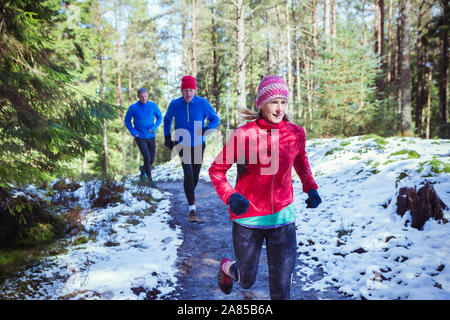 Family jogging on trail in snowy woods