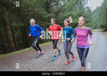 Family jogging on trail in woods Stock Photo