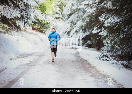 Man jogging on trail in snowy woods Stock Photo