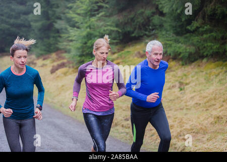 Family jogging on trail in rainy woods Stock Photo