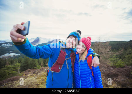 Happy couple hiking, taking selfie on mountaintop Stock Photo