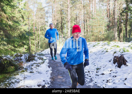 Father and son jogging on trail in snowy woods Stock Photo