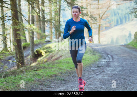 Woman jogging on trail in woods Stock Photo