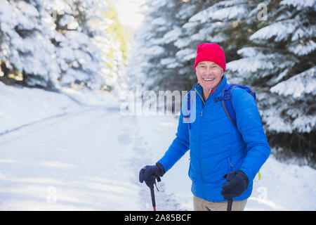 Portrait happy senior man hiking on trail in snowy woods Stock Photo