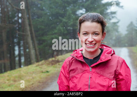 Portrait happy woman hiking on trail in rainy woods Stock Photo