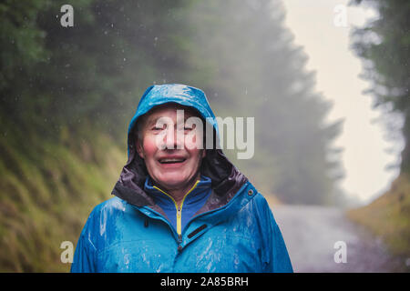 Portrait smiling, active senior man hiking in rainy woods Stock Photo