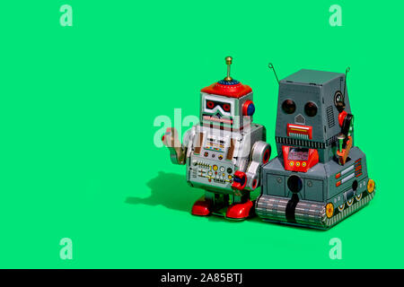 Two antique tin toy robot on green background. Vintage and classic concept free copy space for text. Stock Photo