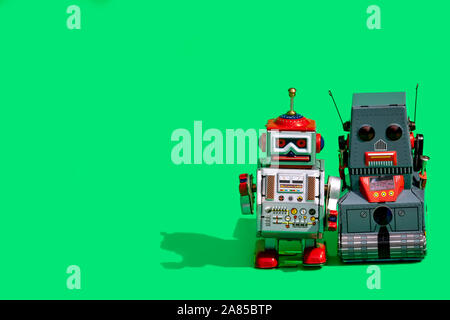 Two antique tin toy robot on green background. Vintage and classic concept free copy space for text. Stock Photo