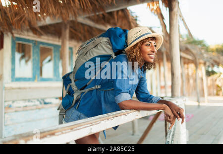 Happy young female backpacker on beach hut patio Stock Photo