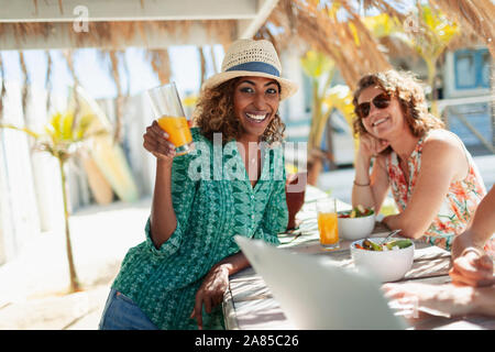 Portrait happy woman drinking cocktail at sunny beach bar Stock Photo