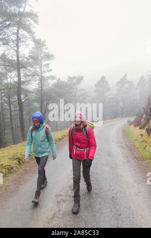 Mother and daughter hiking on wet path on woods Stock Photo