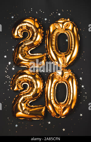 Happy New year 2020 celebration. Bright gold balloons figures, New Year Balloons with glitter stars on dark background. Christmas and new year celebra Stock Photo