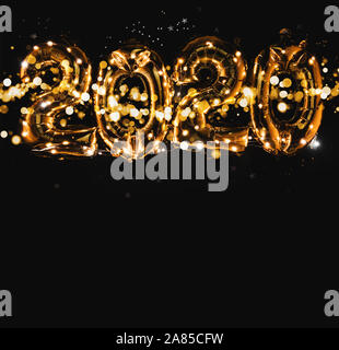 Happy New year 2020 celebration. Bright gold balloons figures, New Year Balloons with glitter stars on dark background. Christmas and new year celebra Stock Photo