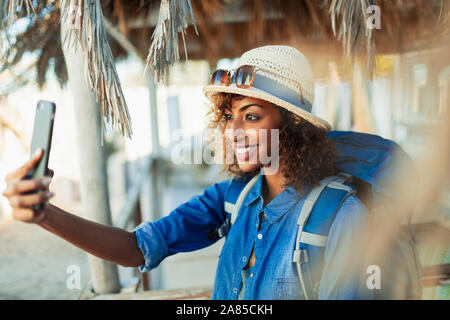 Happy young female backpacker taking selfie with camera phone Stock Photo