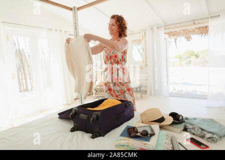 Woman unpacking suitcase in beach hut bedroom Stock Photo
