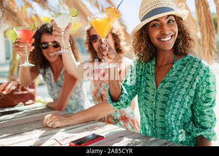 Portrait happy women friends with cocktails at sunny beach bar Stock Photo