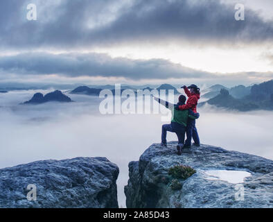 Romantic date in misty mountains. Man shows girlfriend something interesting in far distance. Stock Photo