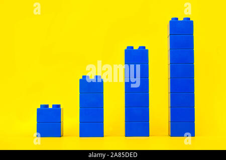 Bar graphs plastic building blocks toy bricks on yellow background. Stock Photo