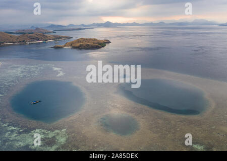 Blue holes are found amid a shallow reef flat on the island of Sebayor in Komodo National Park, Indonesia. These blue holes formed as sink holes. Stock Photo