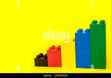 Bar graphs plastic building blocks toy bricks on yellow background. Stock Photo