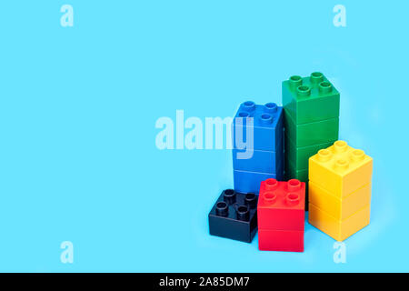Bar graphs plastic building blocks toy bricks on blue background. Stock Photo