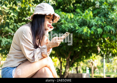 Young happy woman using smartphone. Beautiful smiling woman use of mobile phone in public park. Stock Photo