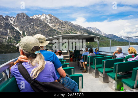 People riding the Ferry Boat on Jenny Lake with the Teton Range behind Stock Photo