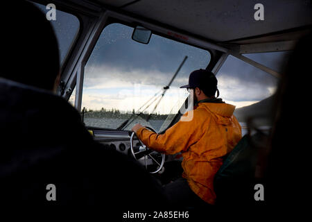 Driver steers a ferry boat through a rain storm on Jenny Lake Stock Photo