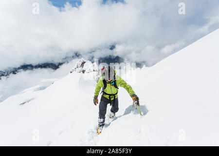 A young man climbs to the summit of Mt. Hood on a cloudy day. Stock Photo