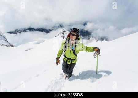 A young man ascents to the summit of Mt. Hood on a cloudy day. Stock Photo