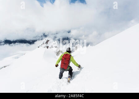 A young man descends from the summit of Mt. Hood on a cloudy day. Stock Photo