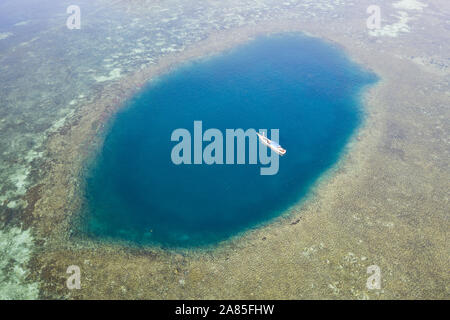 Blue holes are found amid a shallow reef flat on the island of Sebayor in Komodo National Park, Indonesia. These blue holes formed as sink holes. Stock Photo