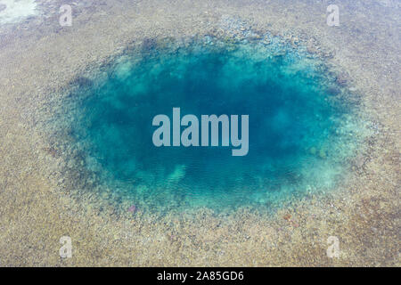 Blue holes are found amid a shallow reef flat on the island of Sebayor in Komodo National Park, Indonesia. These blue holes formed as sink holes. Stock Photo