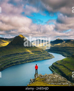 Hiker enjoys views over fjords from a mountain near Funningur on Faroe Islands
