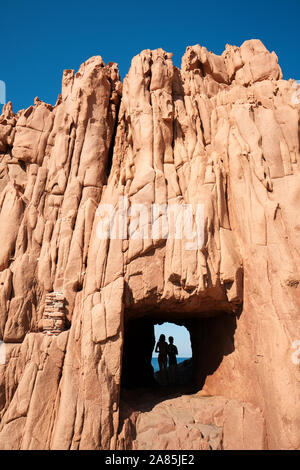 Tourists exploring the Rocce rosse / Porphyry Red Rocks Beach formation ...