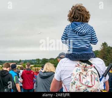 Boy sits on father's shoulders to watch an aeroplane flying at National airshow, East Fortune, East Lothian, Scotland, UK Stock Photo