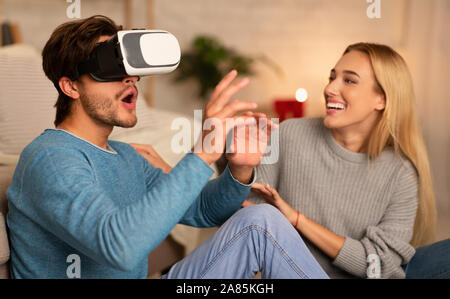 Boyfriend And Girlfriend Using VR Headset Sitting On Floor Indoor Stock Photo