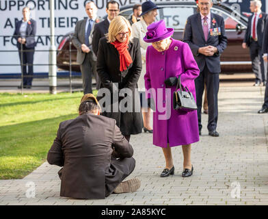 Gardener and veteran John Ahben from Fiji gives a traditional Fijian welcome to Queen Elizabeth II by sitting on the floor in front of her as she arrives for a visit to the Royal British Legion Industries village in Aylesford, Kent, to celebrate the charity's centenary year. Stock Photo