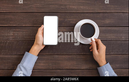 Man holding smartphone with blank screen and drinking coffee Stock Photo