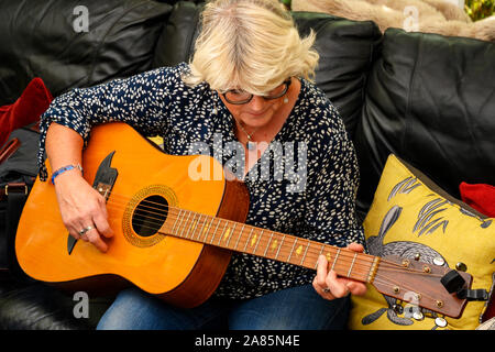 Middle aged woman playing guitar Stock Photo