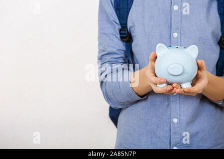Teenager boy holding piggy bank over white background. Financial education savings concept Stock Photo