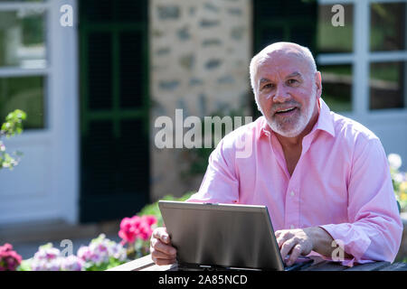 Senior man working outdoors on a laptop Stock Photo