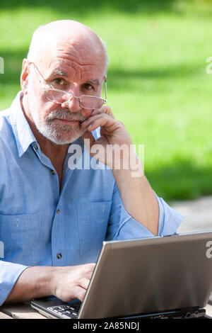 Senior man working on a laptop outside Stock Photo
