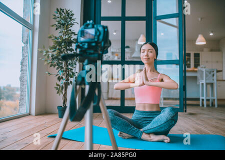 Dark-haired fitness blogger closing eyes while meditating Stock Photo