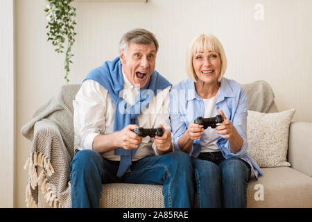 Overjoyed mature couple playing video games at home Stock Photo