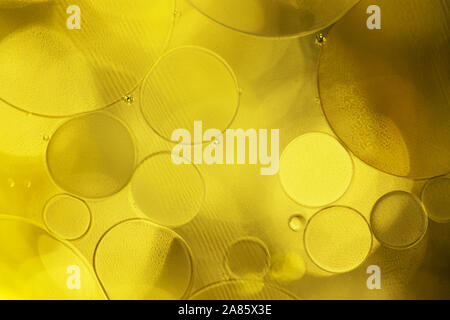 Golden decorative bubbles and circles of oil on the surface of the water. Abstract pattern of a mixture of ingredients. Stock Photo
