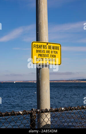 “Fishers beware. Divers are often present, even close to rocks” sign on post, Coast Guard pier, Monterey, California, United States of America. Stock Photo